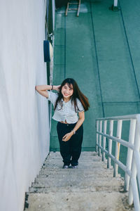 Portrait of smiling young woman standing on staircase