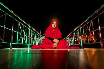 Low angle view of young woman standing on street at night