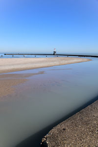 Scenic view of beach against clear blue sky