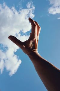 Hand touching the clouds in the blue sky