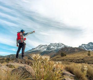 Rear view of man standing on mountain against sky