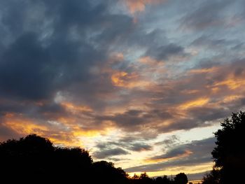 Low angle view of silhouette trees against dramatic sky