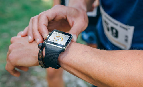 Midsection of athlete checking time while standing outdoors