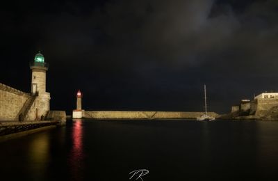 Lighthouse by sea against sky at night