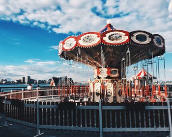 Ferris wheel in city against cloudy sky