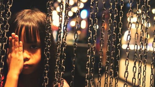 Close-up portrait of cute girl standing by chains