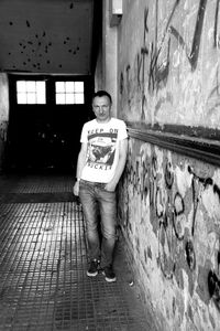 Full length portrait of man standing against wall in building