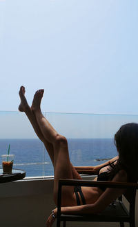 Woman in swimming pool against sea against clear sky