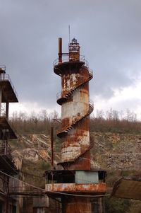 Old tower on field by building against sky