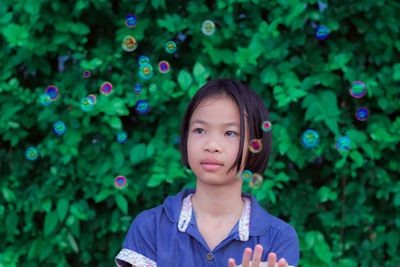 Girl looking at bubbles while standing outdoors