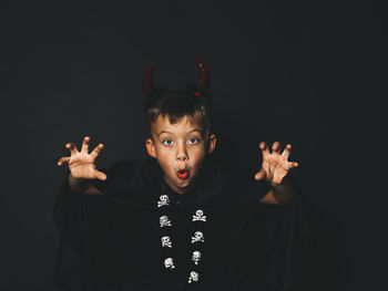 Portrait of boy gesturing against black background