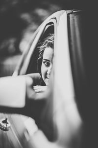 Portrait of woman peeking through car