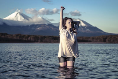 Woman with arms raised standing on mountain against sky