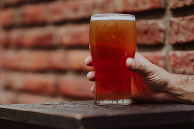 Cropped hand having drink at table