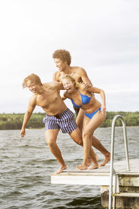 Full length of playful friends jumping into lake