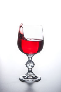 Close-up of red wineglass on table against white background