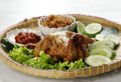 Ayam goreng utuh. deep fried whole chicken served with sambal chilli paste and fresh vegetable. 