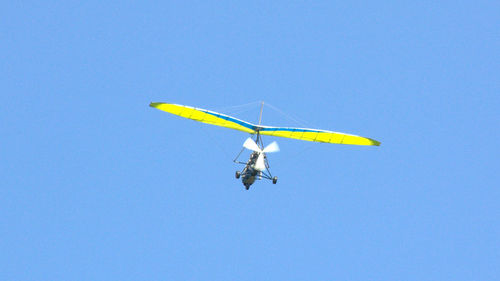 Low angle view of helicopter against clear blue sky