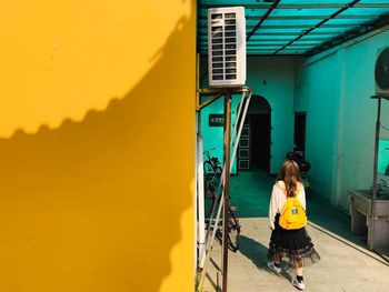 Rear view of woman against yellow building