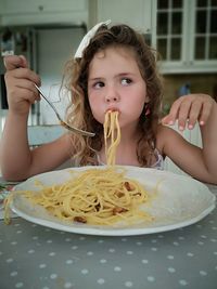 Girl having food in kitchen at home