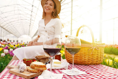 Red wine glasses with defocused young woman in greenhouse on background. focus on wine glasses.