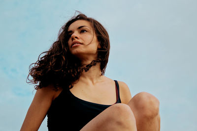 Portrait of young woman looking away against sky