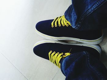 Low section of man wearing shoes on tiled floor