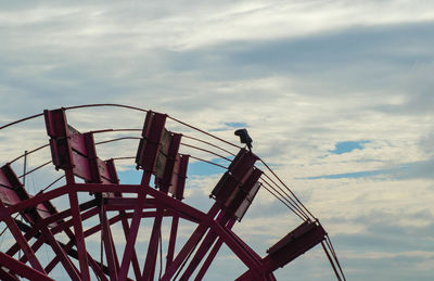 Low angle view of ferris wheel against cloudy sky