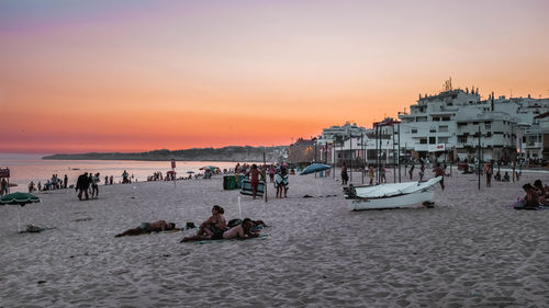 People at beach against sky during sunset