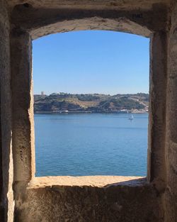 Scenic view of sea against clear blue sky seen through window