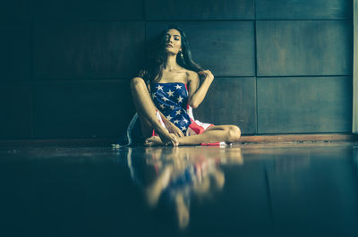 Woman with american flag sitting against wall