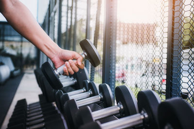 Cropped hand holding dumbbell while exercising in gym