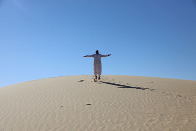 Low angle view of person jumping sand dune