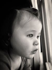 Close-up of cute girl looking through window