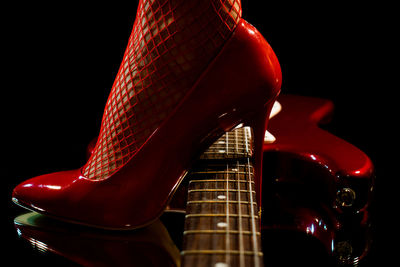 Model wearing high heels and fishnet stockings steps over an electric guitar