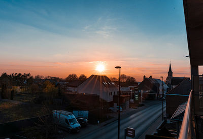 Road amidst buildings against sky during sunset