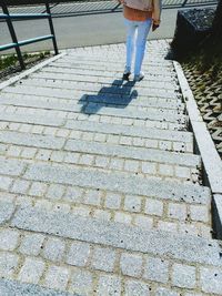 Low section of woman standing on footpath