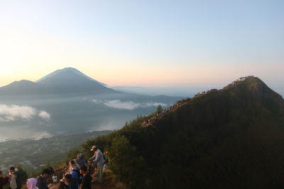 People walking on mountain against clear sky