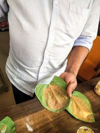 Midsection of man holding fruit on table