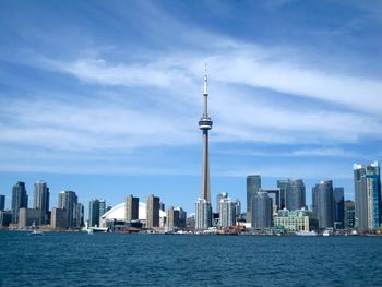 Sea in city against cloudy sky