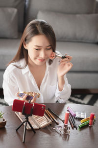 Portrait of young woman holding while sitting on table