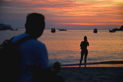 Silhouette people on beach against sky during sunset