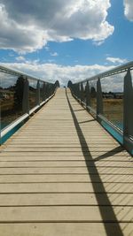 Empty bridge against cloudy sky