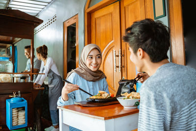 Side view of young woman having food at home