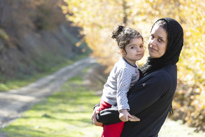 Happy mother and daughter against trees