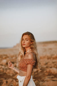 Portrait of beautiful young woman standing on beach