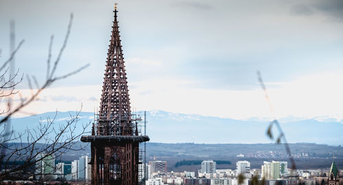 Communications tower in city against sky