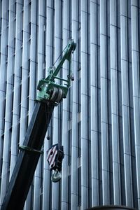 Low angle view of construction equipment against modern skyscrapers