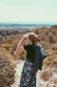 Rear view of woman standing on land against sky