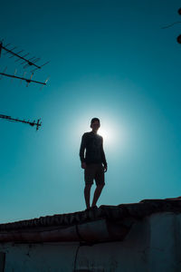 Low angle view of young man against clear blue sky